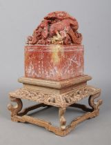 A Chinese carved soapstone seal raised on carved wooden stand. The seal surmounted with a Qilin