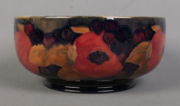 A Moorcroft pottery footed bowl decorated in the Pomegranate design. Signed to base. Diameter 24.