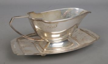 A silver sauceboat with matching stand raised on foot ball feet. Assayed Birmingham 1938 by Davies &