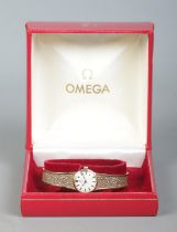 A ladies 9ct gold Omega manual wristwatch on 9ct gold strap. Having satin dial and baton markers. In
