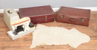 Two vintage leather suitcases along with a cased Singer Stylish sewing machine and a sheepskin rug.