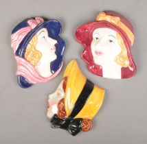 A Cope & Co Art Deco ceramic wall plaque of a lady in a bonnet along with two similar examples.