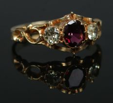 A 19th century gold three stone ring with chased decoration to band. Having central ruby coloured