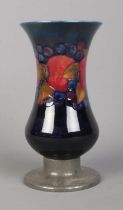 A Moorcroft pottery vase decorated in the Pomegranate design, raised on hammered Tudric pewter base.