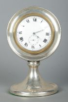 A George V silver desk clock of circular form on pedestal base. Assayed Birmingham 1922 with partial