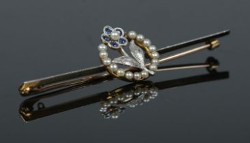 A 15ct gold, platinum, sapphire and pearl knife edge brooch with floral decoration. In case.