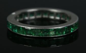 A French platinum and emerald eternity ring, channel set with square cut stones. Stamped with 'Dog