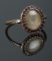 A Georgian yellow metal mourning ring with garnet surround. Size N 1/2. 2.05g.