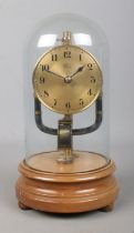 An early 20th century Bulle electro magnetic clock under glass dome, raised on wooden stand. 26.5cm.