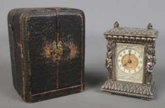 An ornate metal miniature desk clock in fitted leather case. (9cm)