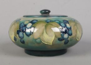 A Moorcroft pottery powder bowl decorated with blueberries. Diameter 16cm. Replacement lid.