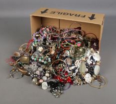 A large box of costume jewellery including various necklaces and earrings.