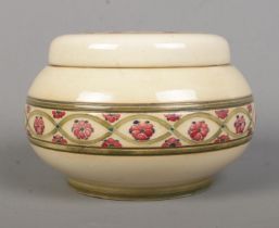 A Moorcroft lidded pot decorated with red Forget Me Nots. Signed to base. Height 10cm. Lid glued