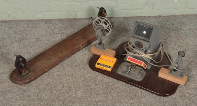 A Nizo 16mm film editor along with two 16mm film tapes and similar reel to reel stand.