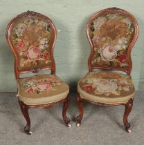A near pair of Victorian carved nursing chairs with tapestry style upholstery.