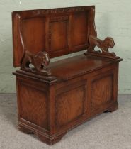 A carved and panelled oak monks bench. With lion mask handles and under seat storage.