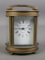 An Elliot and Son brass and glass carriage clock in oval form.