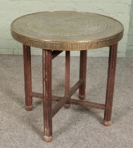An Indian brass top table with folding wooden base. Diameter of top 60cm.