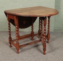 An oak gate leg table with barley twist supports.