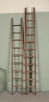 A large set of wooden extension ladders and a single set of ladders