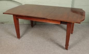 A mahogany inlaid dining table with square tapering legs sat on brass castors. Comes with one