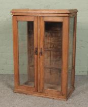 A small stripped oak glazed cabinet. Height 94cm, Width 64cm, Depth 38cm.
