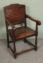 An oak wainscot armchair with carved detail to panel. Damage to panel split in the middle