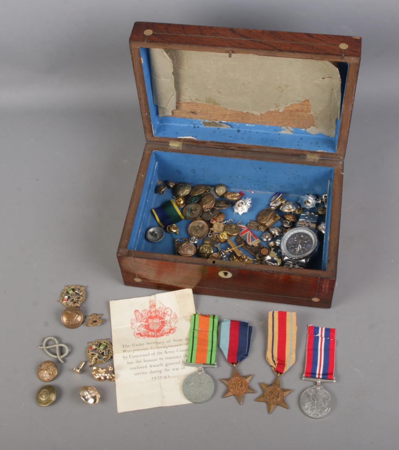 A box of assorted militaria to include set of WWII British Medals, buttons, cap badges, etc.