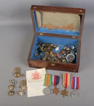 A box of assorted militaria to include set of WWII British Medals, buttons, cap badges, etc.