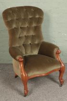 A Victorian button back armchair with green upholstery and scrolling mahogany frame on brass casters