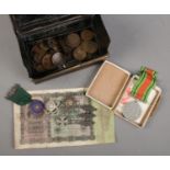 A tin cash box with contents of coins and medals. Includes The Defence Medal, silver cycling medal