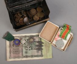 A tin cash box with contents of coins and medals. Includes The Defence Medal, silver cycling medal