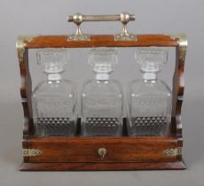 An oak three decanter tantalus with metal mounts.