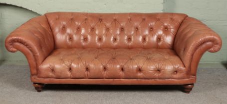 A brown leather chesterfield type sofa raised on bun feet. Length 250cm approx Some discolouration