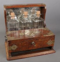 A George V oak tantalus with brass mounts mirrored back and fitted interior with two glasses.