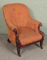 A Victorian mahogany armchair with scrolling frame on brass castors.