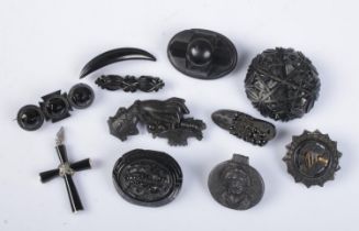 Ten jet and similar brooches along with a white metal mounted crucifix pendant.