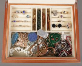 A wooden jewellery box with contents of costume jewellery. Includes rings, enamel pendants etc.