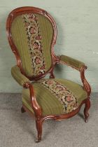 A Victorian carved open armchair with tapestry style upholstery. Missing one castor