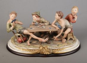 A large Capodimonte figure group titled 'The Cheat' raised on wooden plinth.