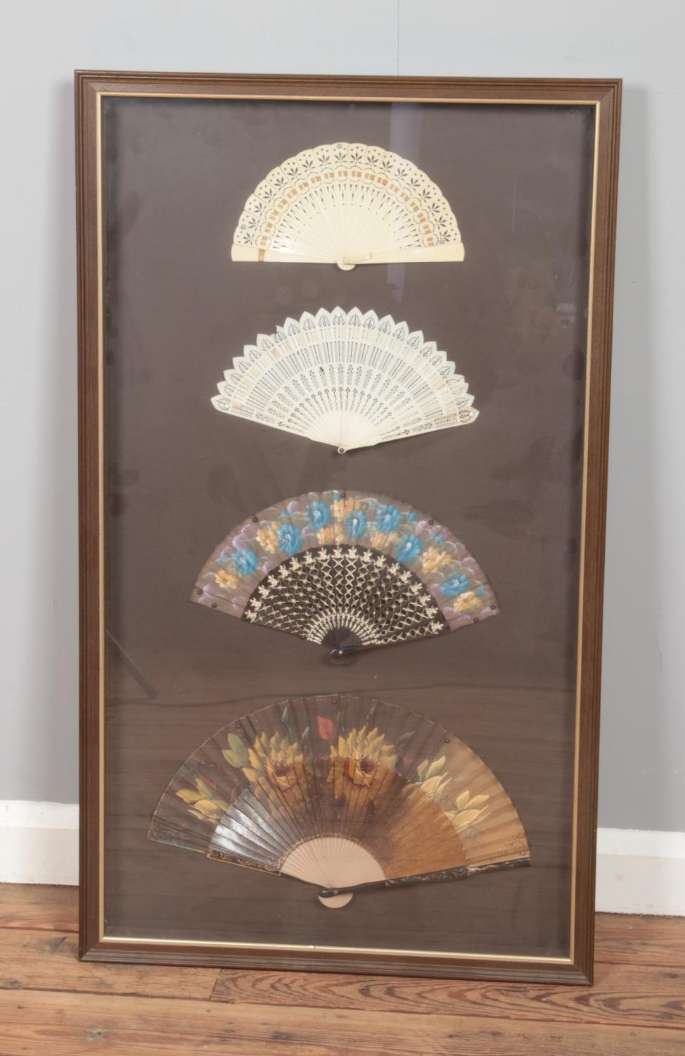 A framed display of four oriental hand fans to include floral and gilt examples. Approx.