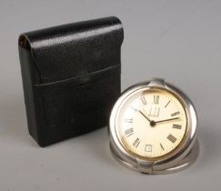 A Dunhill quartz travel alarm clock in case. With Roman numeral markers and date display. Clock
