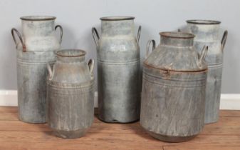 Five reproduction metal milk churns, including hinged example.