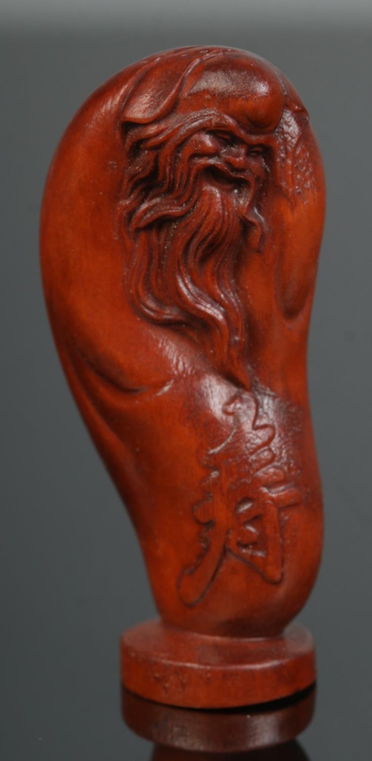 A hand carved hardwood netsuke of the god of longevity, signed.
