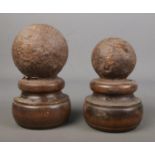 Two similar canon balls on wooden turned mounts.