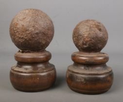 Two similar canon balls on wooden turned mounts.