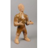 A partially glazed Chinese terracotta tomb figure formed as a servant with outstretched arms.