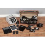 A vintage suitcase containing a variety of cameras and equipment along with bill counter and small