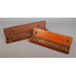 Two wooden cased brass sliding rules; one marked for 'Drawing Office Supplies Ltd'.