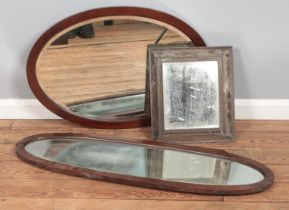 Three bevelled edge glass mirrors including two oval examples.